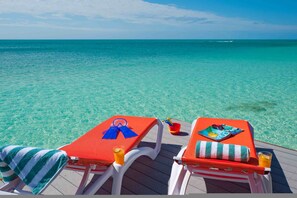 Two sun loungers with towels and drinks on a wooden deck overlooking turquoise water. - Villa La Percha With 4 Bedrooms and 4 5 Bathrooms (Providenciales)
