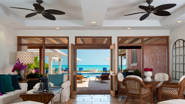 A spacious living area with a view of the beach, furnished with a sofa, chairs, and a coffee table. - Villa La Percha With 4 Bedrooms and 4 5 Bathrooms (Providenciales)