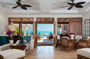 A spacious living area with a view of the beach, furnished with a sofa, chairs, and a coffee table. - Villa La Percha With 4 Bedrooms and 4 5 Bathrooms (Providenciales)