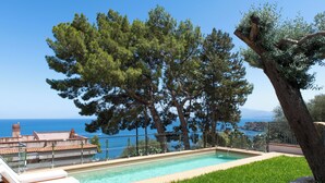 A swimming pool with a view of the sea, surrounded by trees and a fenced area. - Sea Frame Design Apartments with Pool by Wonderful Italy (Santa Flavia)