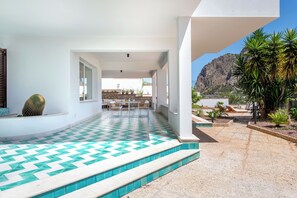 Eine moderne Außenpatio mit einem geometrischen Fliesenboden, einem Essbereich und Blick auf eine Berglandschaft.