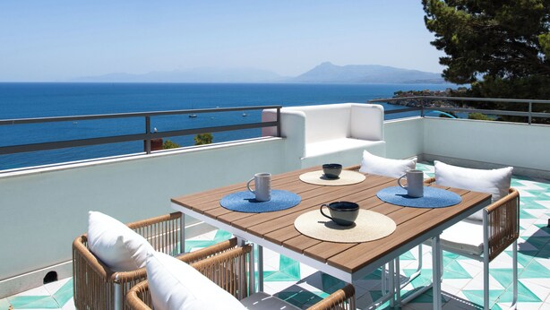 A terrace with a wooden table, wicker chairs, and a view of the sea. - Sea Frame Design Apartments with Pool by Wonderful Italy (Santa Flavia)