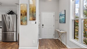 A modern kitchen with a stainless steel refrigerator, wooden flooring, and a white door. - Downtown Condo - 2BR, 2BA, Walk to Everything! (Raleigh)