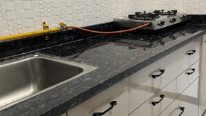 Eine Küche mit Spüle aus Edelstahl, einem Gasherd und einer schwarzen Arbeitsplatte.