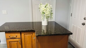 Una cocina con encimera de granito, armarios de madera y un jarrón blanco con flores.