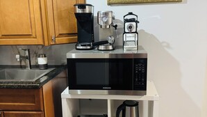 Una cocina con armarios de madera, cafetera, microondas, horno Samsung, molinillo de café y hervidor.