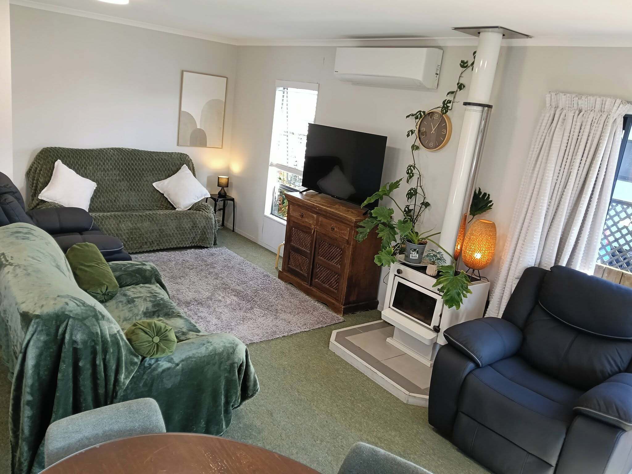 A living room with a sofa, a television, a fireplace, and a window.