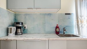 A kitchen with a marble countertop, a coffee maker, a kettle, a bottle of dish soap, and a stainless steel sink. - Apartment "Haus Rosengarten" with Balcony and Wi-Fi (Friedenweiler)