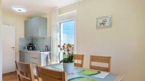 A dining area with a table, chairs, a potted plant, and a kitchen in the background. - Apartment "Haus Rosengarten" with Balcony and Wi-Fi (Friedenweiler)