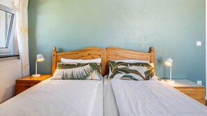 A double bed with a wooden headboard, two bedside tables with lamps, and a window with curtains. - Apartment "Haus Rosengarten" with Balcony and Wi-Fi (Friedenweiler)