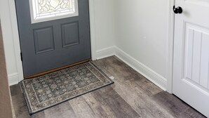 A gray door with a decorative glass panel, a wooden 'home' sign, and a doormat. - Charming 3-bedroom minutes from OWA (Foley)