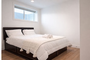A bedroom with a bed, pillows, a blanket, and a window. - 20 Min Airport|Spacious 2BR Suite| Modern| Bright (Beaumont)