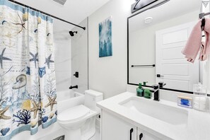 Een moderne badkamer met een douche, toilet en wastafel.