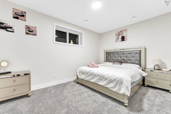 Een slaapkamer met een bed, nachtkastjes, een kaptafel en kunstwerken aan de muur.