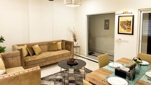 Una sala de estar moderna con un sofá color beige, una mesa de centro redonda y un comedor con una mesa de madera dispuesta para dos personas.