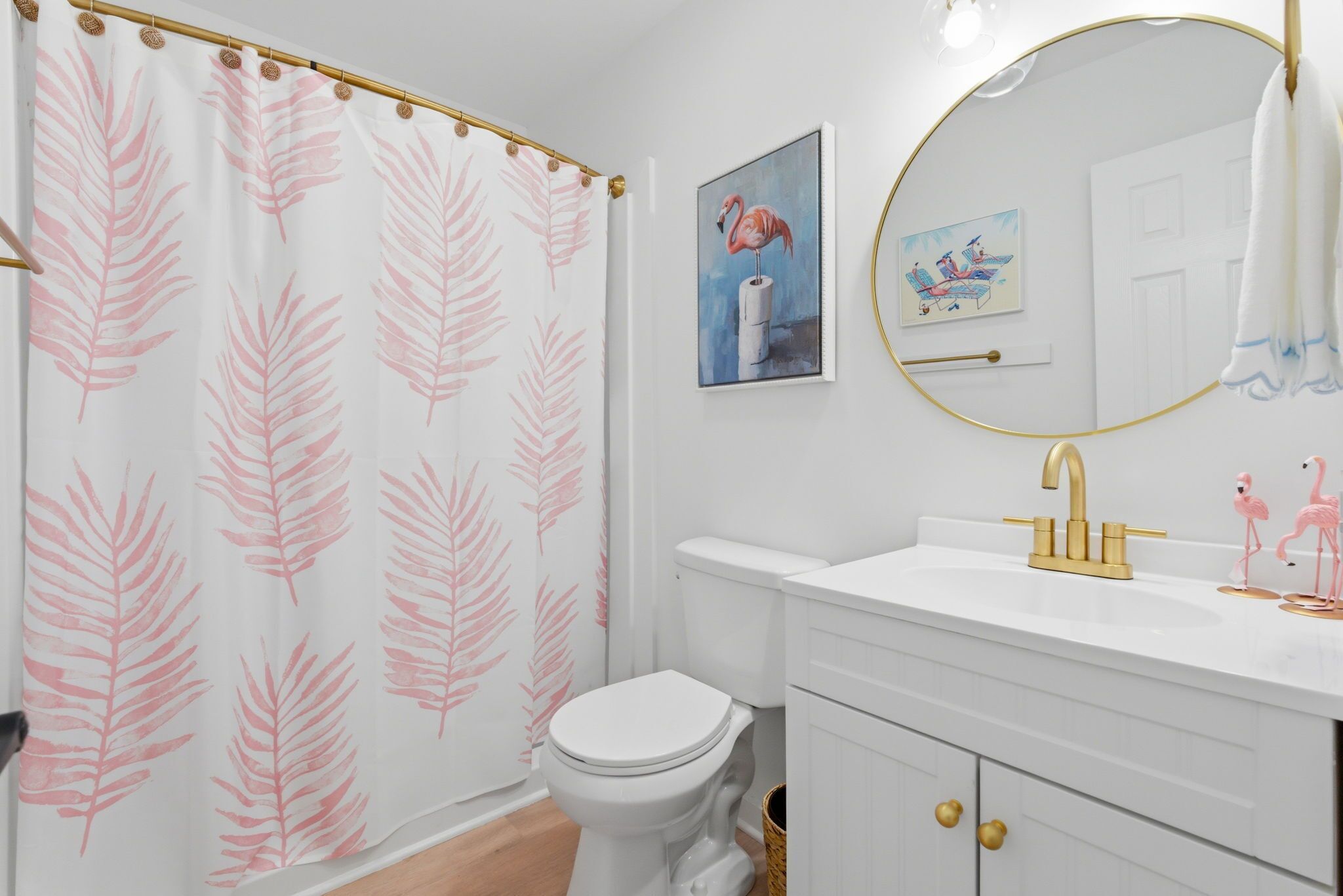 Ein Badezimmer mit Toilette, goldenem Wasserhahn, Waschbecken und einer Duschvorhang mit Blättermotiv.