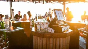 A bar area with a wooden counter, bottles of Bacardi, and a digital menu display. - The Beach! | Pool, Hot Tub, Gym, Game Room, Tennis (Ruskin)