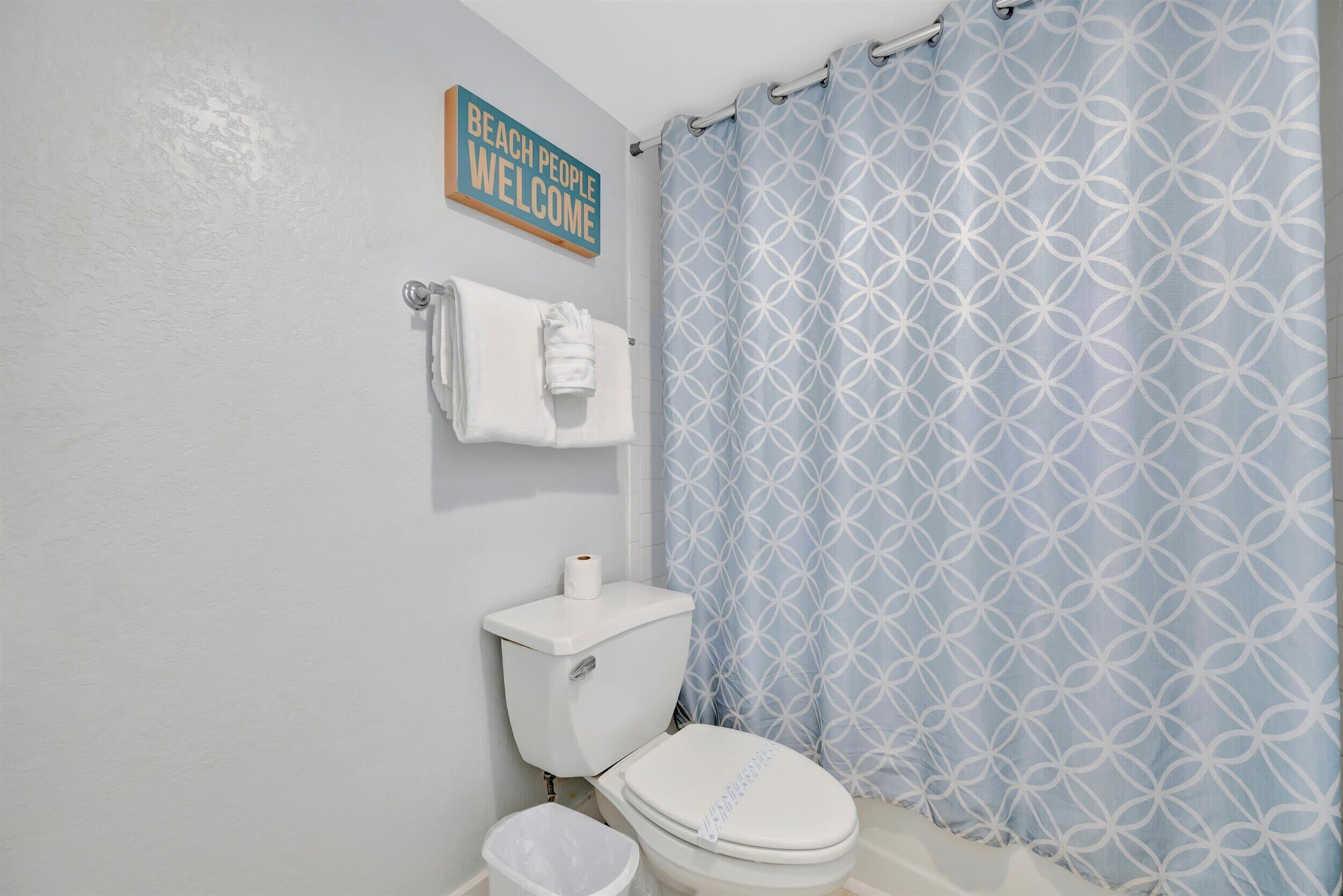 A bathroom with a toilet, a towel rack, and a shower curtain.