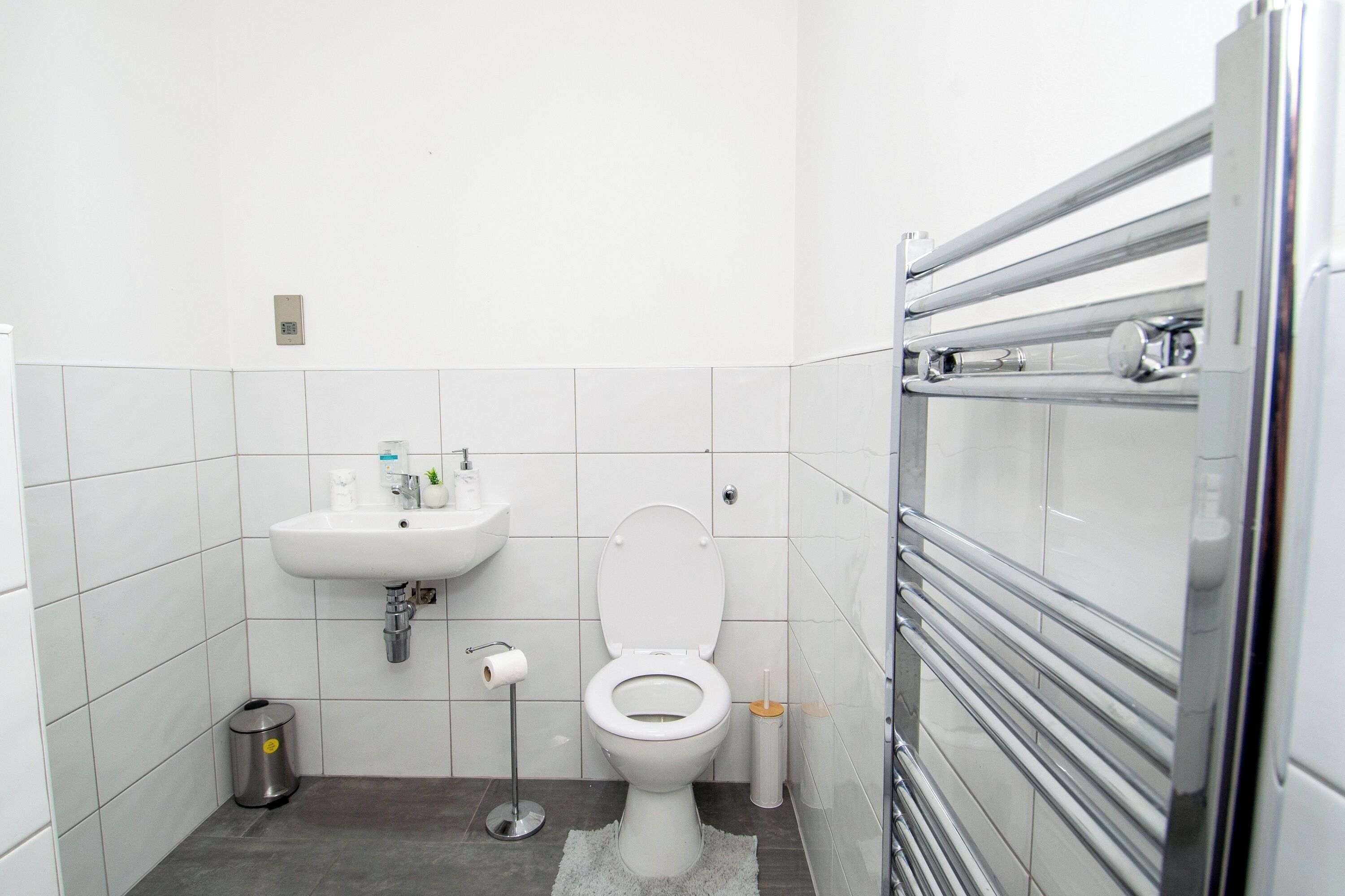A small, modern bathroom with a white toilet, a sink, and a trash can.