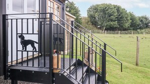 Een trap die leidt naar een gebouw, met een metalen hekwerk en een silhouet van een hond op de muur.