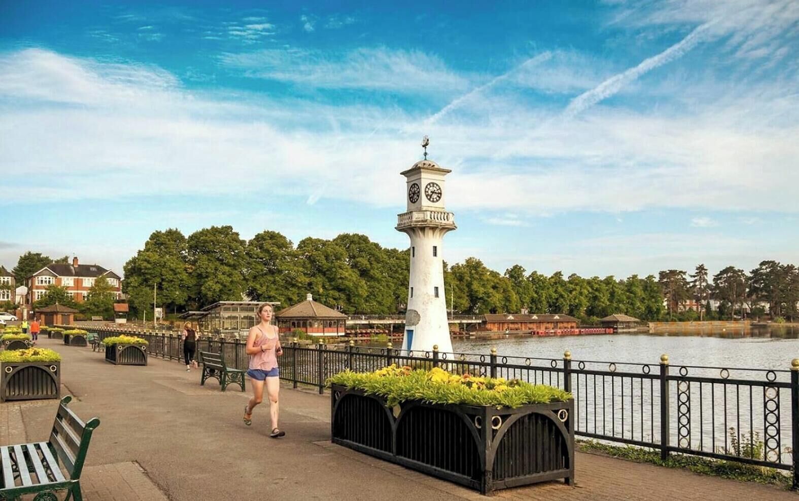 A waterfront promenade with a white lighthouse, benches, and a path.