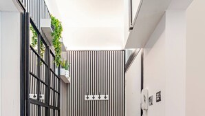 A narrow hallway with a black and white striped wall, a potted plant, a door with a phone, and a doormat with the text "THE SHOELESS". - Modern 1 Bedroom Flat in Aberdeen City Center, With Parking. (Aberdeen)