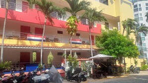 A multi-story building with balconies, palm trees, and a covered outdoor seating area. - Spacious 65sqm Luxury Loft Studio Type Apartment 101b (Pattaya)