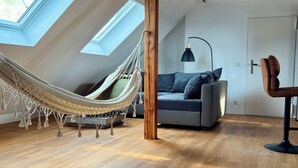 A spacious loft bedroom with a hammock, a sofa, and a desk.