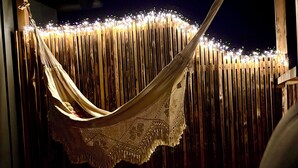 A hammock under a wooden ceiling with string lights. - Beautiful large vacation apartment with private terrace in the Hunsrück. 70 sqm (Norath)