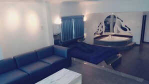 Ein modernes Wohnzimmer mit einem dunkelblauen Sofa, einem Marmortisch und einem außergewöhnlichen, runden Waschbecken mit Spiegel.