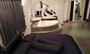 A bedroom with a bed, a bathroom with a bathtub, and a mirror. - 115sqm Studio Type Jacucci - Apartment 301 (Pattaya)