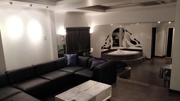 Ein modernes Wohnzimmer mit einem schwarzen Ledersofa, einem Marmor-Couchtisch und einem einzigartigen Wandkunstwerk.