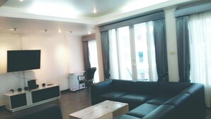 Ein modernes Wohnzimmer mit einer großen Couch, einem Flachbildfernseher und einem kleinen Couchtisch.