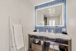 A bathroom with a white sink, a large mirror, and a towel rack.