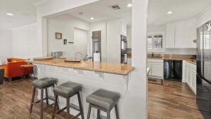 A modern kitchen with white cabinetry, a granite countertop, and a built-in dishwasher.