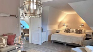 A bedroom with a bed, bedside tables, a nightstand, a hanging light fixture, a door, and a view of a balcony. - Gemütliche 2,5 Zimmer unter Reet in SPO (Sankt Peter-Ording)