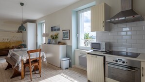 A kitchen with a microwave, oven, and a window with a view. - Charming Apartment in Locquirec with Sea View (Locquirec)