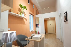 A modern hotel room with a wooden desk, a chair, a lamp, and a potted plant.