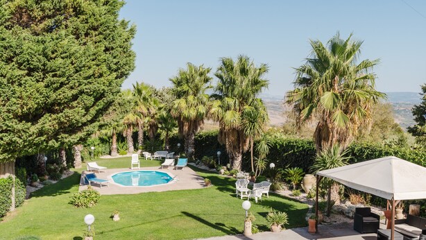 A backyard with a swimming pool, lounge chairs, and a covered patio area. - Casa vacanza Margiulu’ (Partanna)