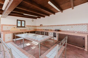 Una cocina con salpicadero de azulejos, vigas de madera, una ventana y piso de azulejos.