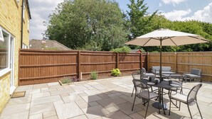 A patio with a table and chairs, a wooden fence, and a large umbrella. - 22 Old Chapel Close (Kidlington)