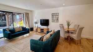 A modern living room with two teal sofas, a wooden coffee table, and a TV. - The Retreat (Ferndown)