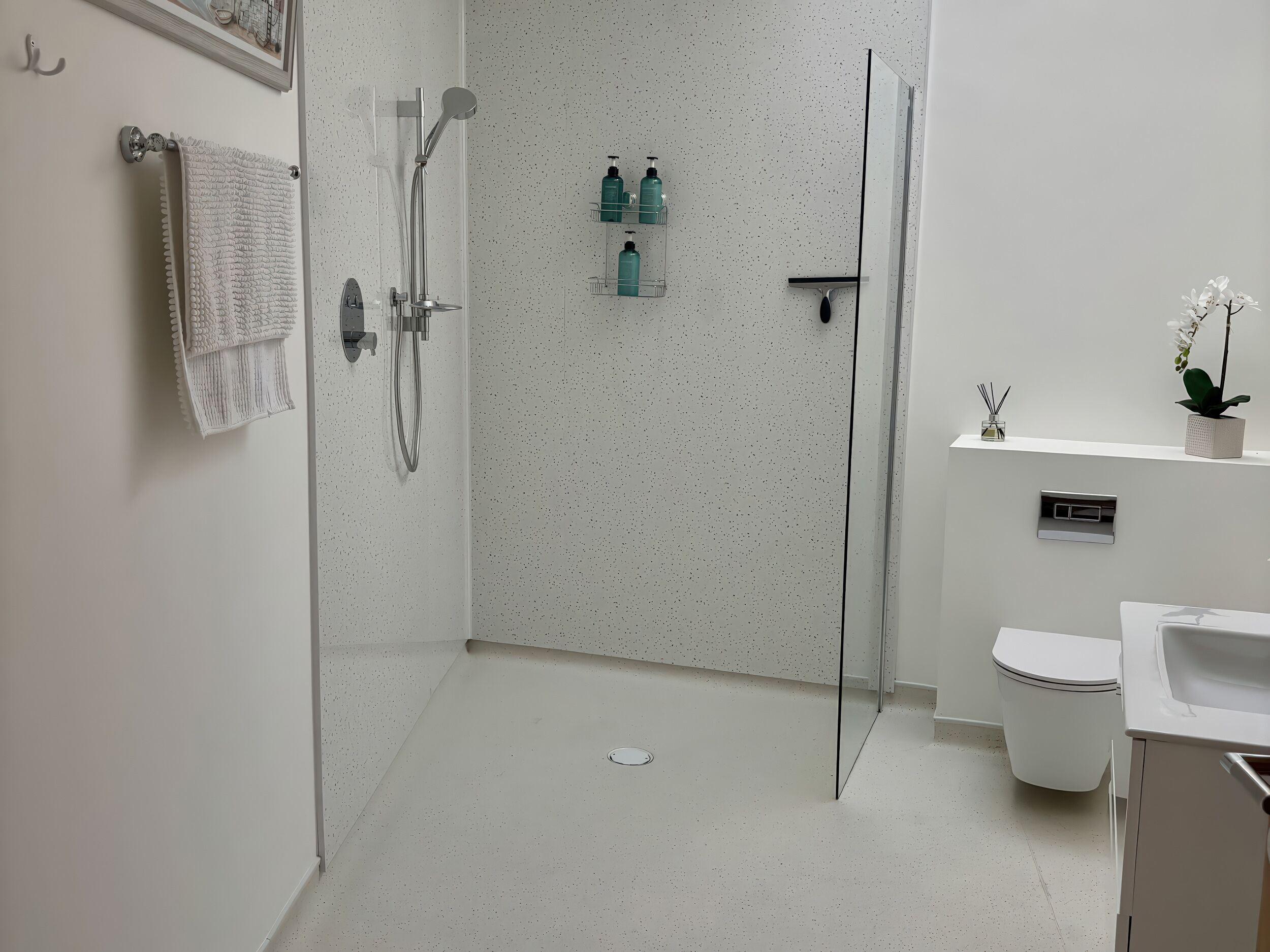 A modern bathroom with a shower, toilet, and sink.