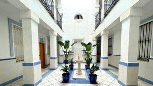 A hotel corridor with a tiled floor, potted plants, a central fountain, and a statue. - Very central studio with A/C, equipped kitchen, and elevator. (Málaga)