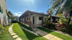 A residential property with a paved pathway, well-maintained lawn, and a variety of plants. - Casa em Natal com Piscina a 290m da Praia (Natal)