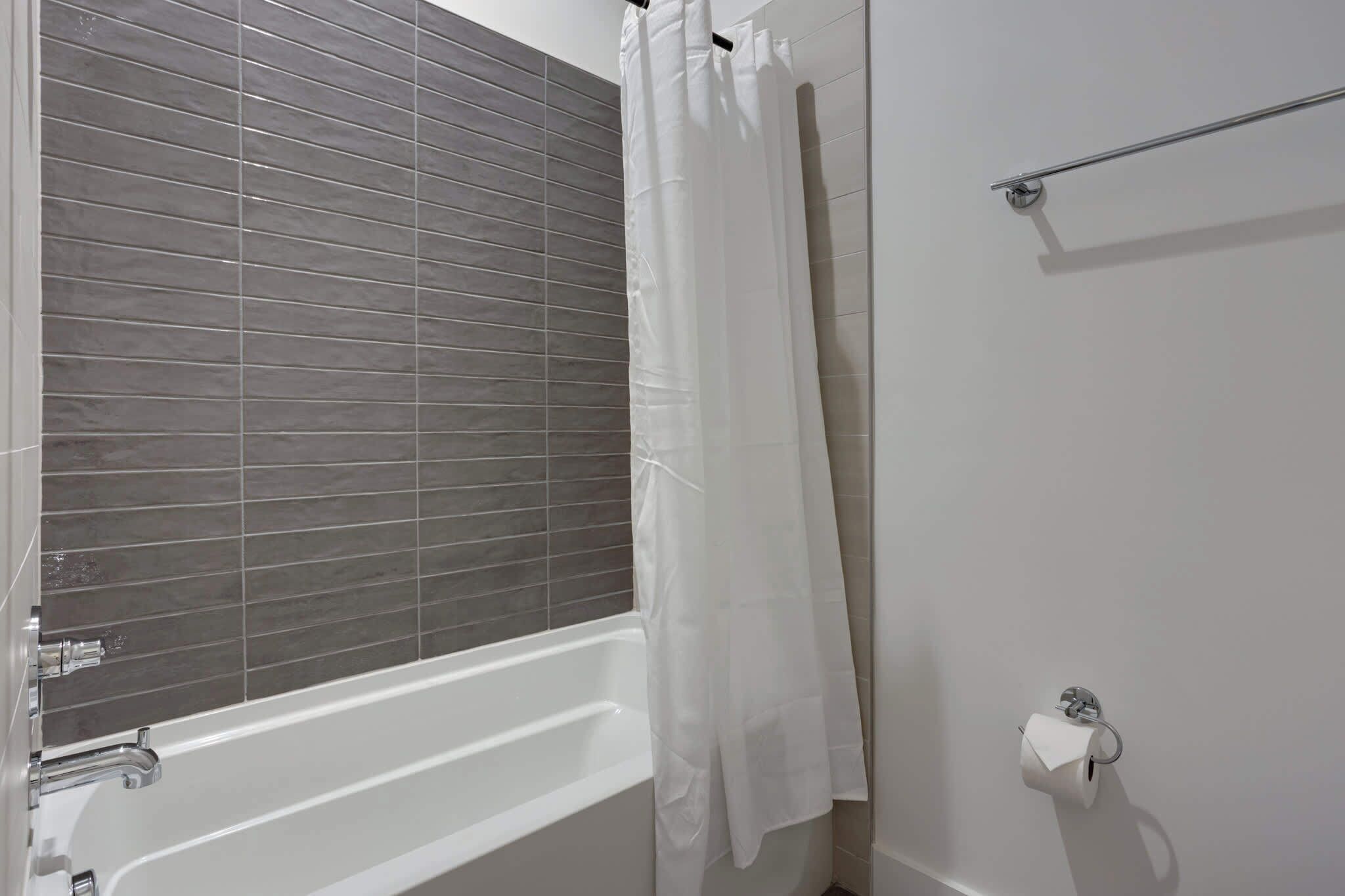 Une salle de bain avec une baignoire, un rideau de douche et un porte-rouleau de papier toilette.