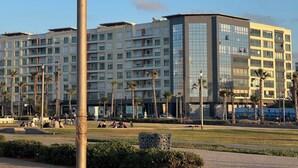 Un hotel moderno de varios pisos con balcones, un patio ajardinado y palmeras.
