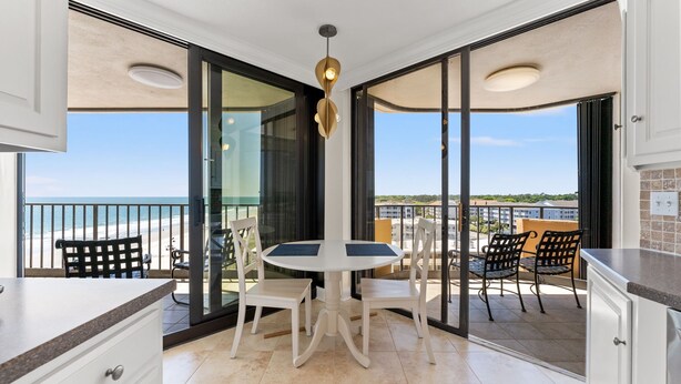 Varanda com mesa e cadeiras, vista para a praia e luminária no teto.