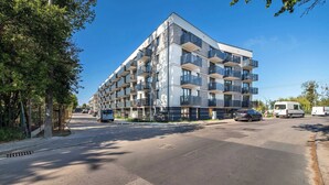 Een modern meerhoog gebouw met balkons, een heldere lucht en voertuigen op de straat.