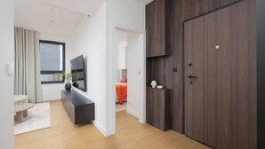 A modern living room with a flat-screen TV, a dark wood wardrobe, and a light-colored sofa.